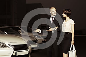 Young couple collecting new car at dealership lot