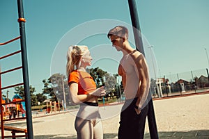 Young couple communicates while standing by a horizontal bar