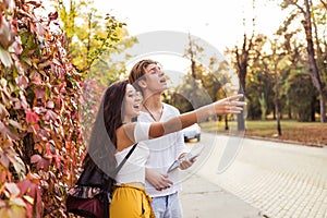 Young couple consulting a city guide and the digital tablet gps in the street searching locations