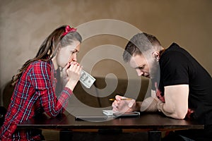 Young couple counts money at the table and looks thoughtfully at the numbers