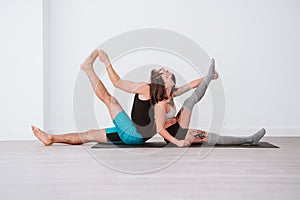 young couple Couple practicing acro yoga in white studio or gym. Healthy lifestyle