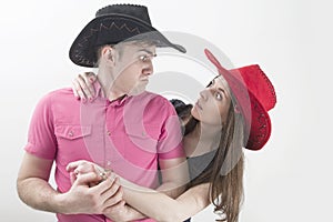 Young couple with cowboy hats making silly faces on white