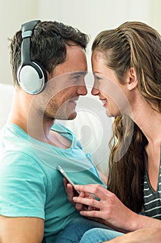 Young couple cuddling while listening to music on mobile phone