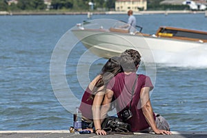 Young couple cuddling while sitting on the pier, Venice, Italy