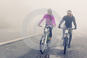 Young Couple Cycling Through The Fog