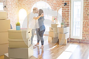 Young couple dancing around cardboard boxes at new home, celebrating smiling very happy new house