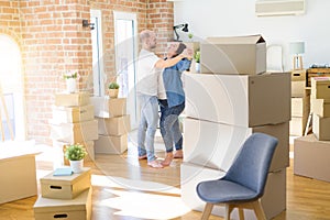 Young couple dancing around cardboard boxes at new home, celebrating smiling very happy new house