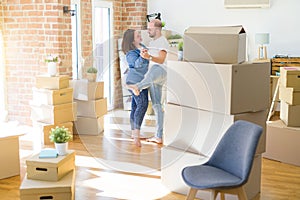 Young couple dancing around cardboard boxes at new home, celebrating smiling very happy new house