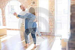 Young couple dancing around cardboard boxes at new home, celebrating smiling very happy new house