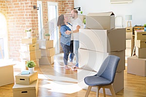 Young couple dancing around cardboard boxes at new home, celebrating smiling very happy new house