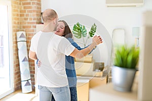 Young couple dancing around cardboard boxes at new home, celebrating smiling very happy new house