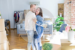 Young couple dancing around cardboard boxes at new home, celebrating smiling very happy new house