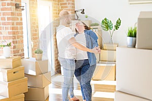 Young couple dancing around cardboard boxes at new home, celebrating smiling very happy new house