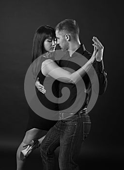 Young couple dancing on a dark background
