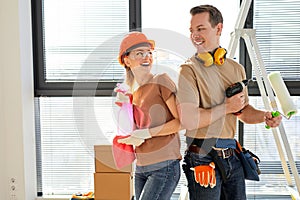 Young couple dancing, having fun after making repairs, painting walls in new home