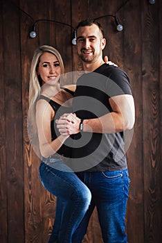 Young couple dancing latin music: Bachata, merengue, salsa. Two elegance pose on cafe with brick walls