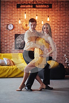 Young couple dancing latin music: Bachata, merengue, salsa. Two elegance pose on cafe with brick walls