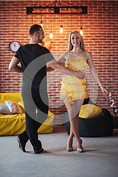 Young couple dancing latin music: Bachata, merengue, salsa. Two elegance pose on cafe with brick walls