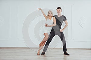 Young couple dancing latin music: Bachata, merengue, salsa. Two elegance pose on white room