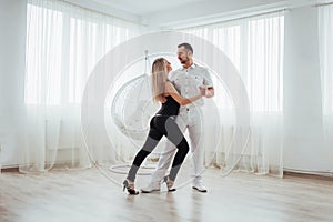 Young couple dancing latin music: Bachata, merengue, salsa. Two elegance pose on white room