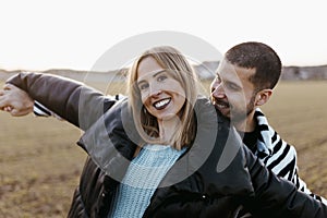Young couple dancing outdoor through meadow in countryside. Boyfriend and girlfriend in love