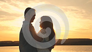 Young couple dancing at sunset on beach. Loving man and woman dance in bright rays of sun on the background of the lake