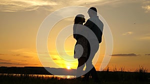 Young couple dancing at sunset on beach. Loving man and woman dance in bright rays of sun on the background of the lake