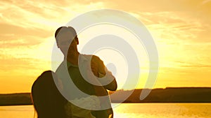 Young couple dancing at sunset on beach. Loving man and woman dance in bright rays of sun on the background of the lake