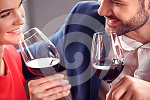 Young couple on date in restaurant sitting drinking wine flirting cheerful close-up