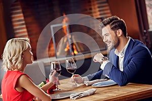 Young couple on date in restaurant sitting drinking wine talking joyful