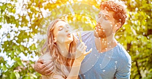 Young couple daydreaming about their future blowing dandelion seeds