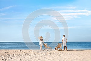 Young couple  deck chairs on sandy beach