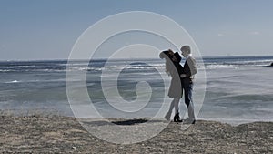 Young couple descend from sand hill holding each other`s hands, sunny spring day