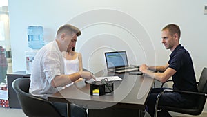 A young couple is discussing a contract with a car dealer at a car dealership. A husband and wife communicate with a car