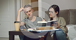 Young couple discussing a joint project or design of a new apartment working together sitting on the floor at home