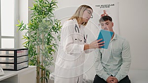 Young couple doctor and patient using touchpad having medical consultation at clinic