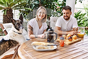 Young couple with dog smiling happy having breakfast at terrace