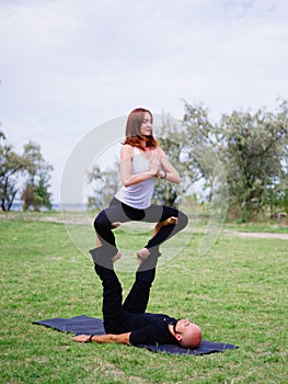 Young couple doing acro bird yoga pose. Healthy lifestyle modern activity.