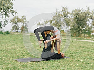 Young couple doing acro bird yoga pose. Healthy lifestyle modern activity.