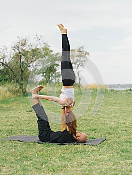 Young couple doing acro bird yoga pose. Healthy lifestyle modern activity.