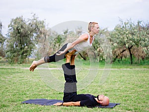 Young couple doing acro bird yoga pose. Healthy lifestyle modern activity.