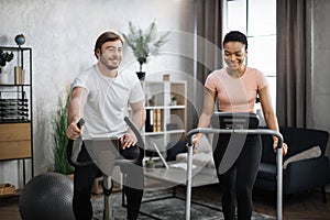 Young couple doing cardio on stationary bike and treadmill.