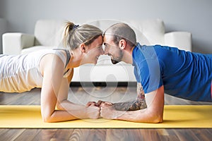 Young couple doing exercise at home in living room.