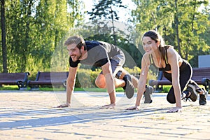 Young couple doing exercise together while working out outdoors in park