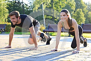 Young couple doing exercise together while working out outdoors in park