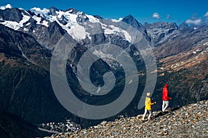 Young couple doing Nordic walking in the mountains, rear view. An active couple is engaged in Hiking.