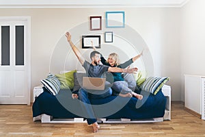 Young couple doing shoppings online on the sofa at home with laptop, happy and smiling photo