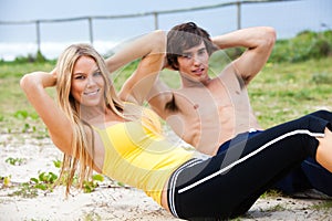 Young Couple Doing Sit-Ups By the Ocean