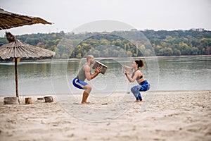 Young couple doing squats on the beach