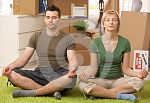 Young couple doing yoga at new house